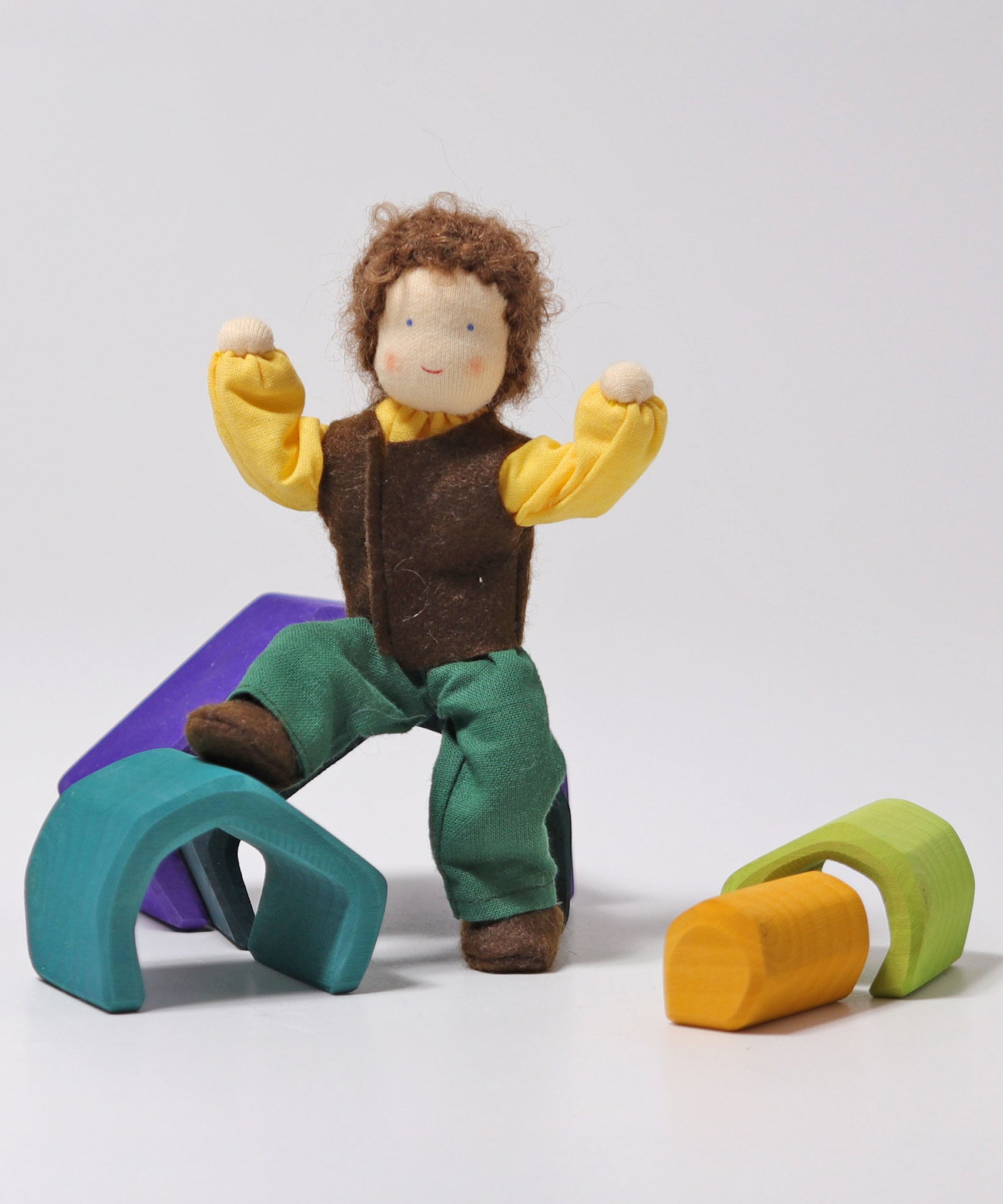 Grimm's Brown Haired Man Doll - Erle has its foot resting on a wooden Grimm's block and its arms bent upward showing the flexibility of the dolls arms and legs.