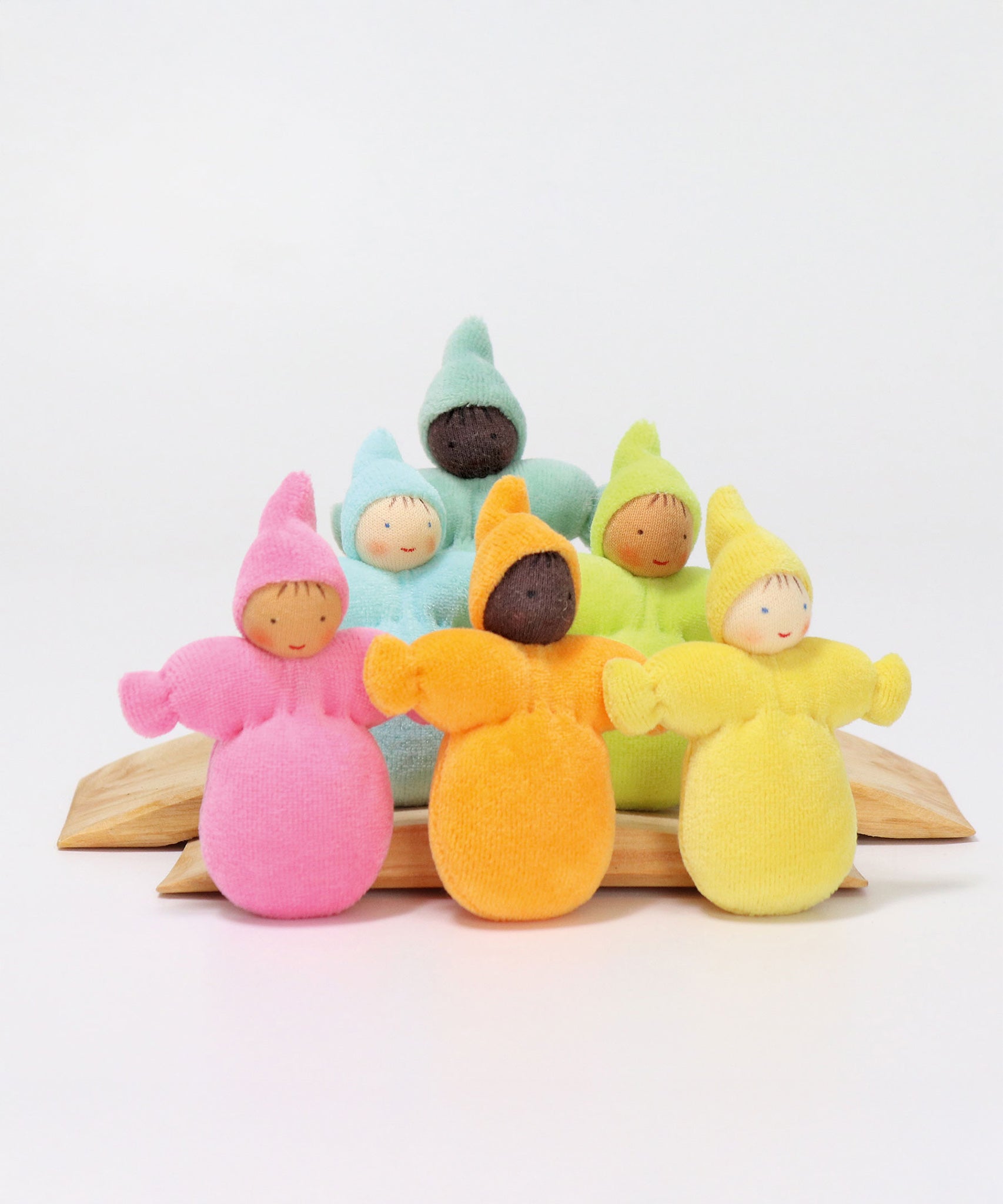 The Grimm's Pastel Dwarfs dolls stood on natural wooden boards, on a light grey background