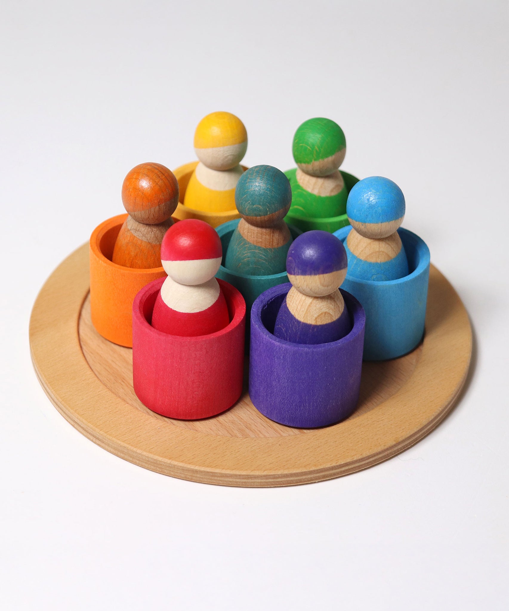 The Grimm's Wooden Friends Peg Dolls sat in the Wooden Grimm's bowls on a cream background