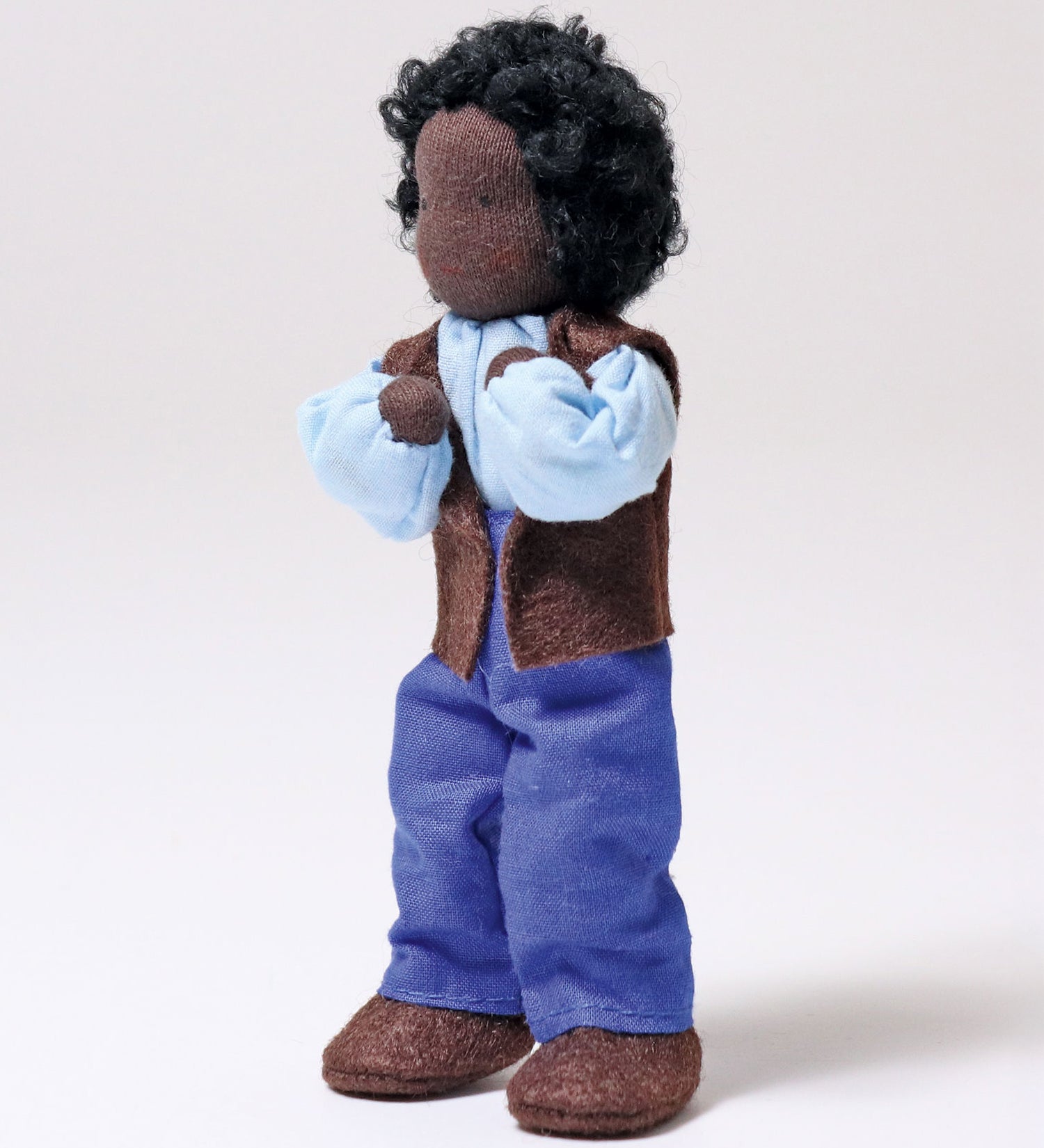 Grimm's Handmade Doll - Mr Ebony is stood up with its arms bent towards its face at the elbows, showing off the flexibility of the doll. The image is on a light grey background