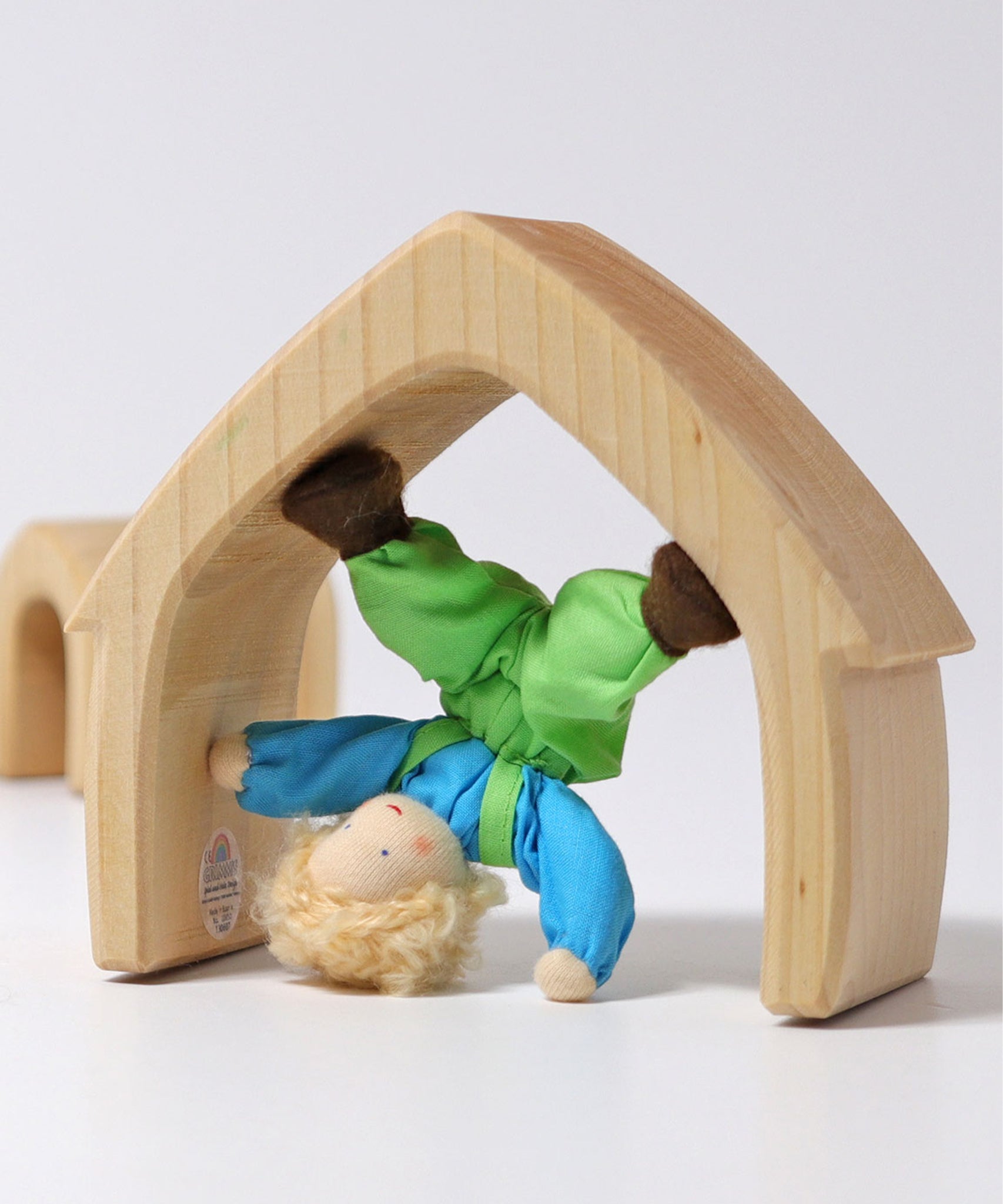 Grimm's Blond Boy Doll - Linde is playing in one of the Grimm's Natural Wooden arches and is upside down doing a headstand. 