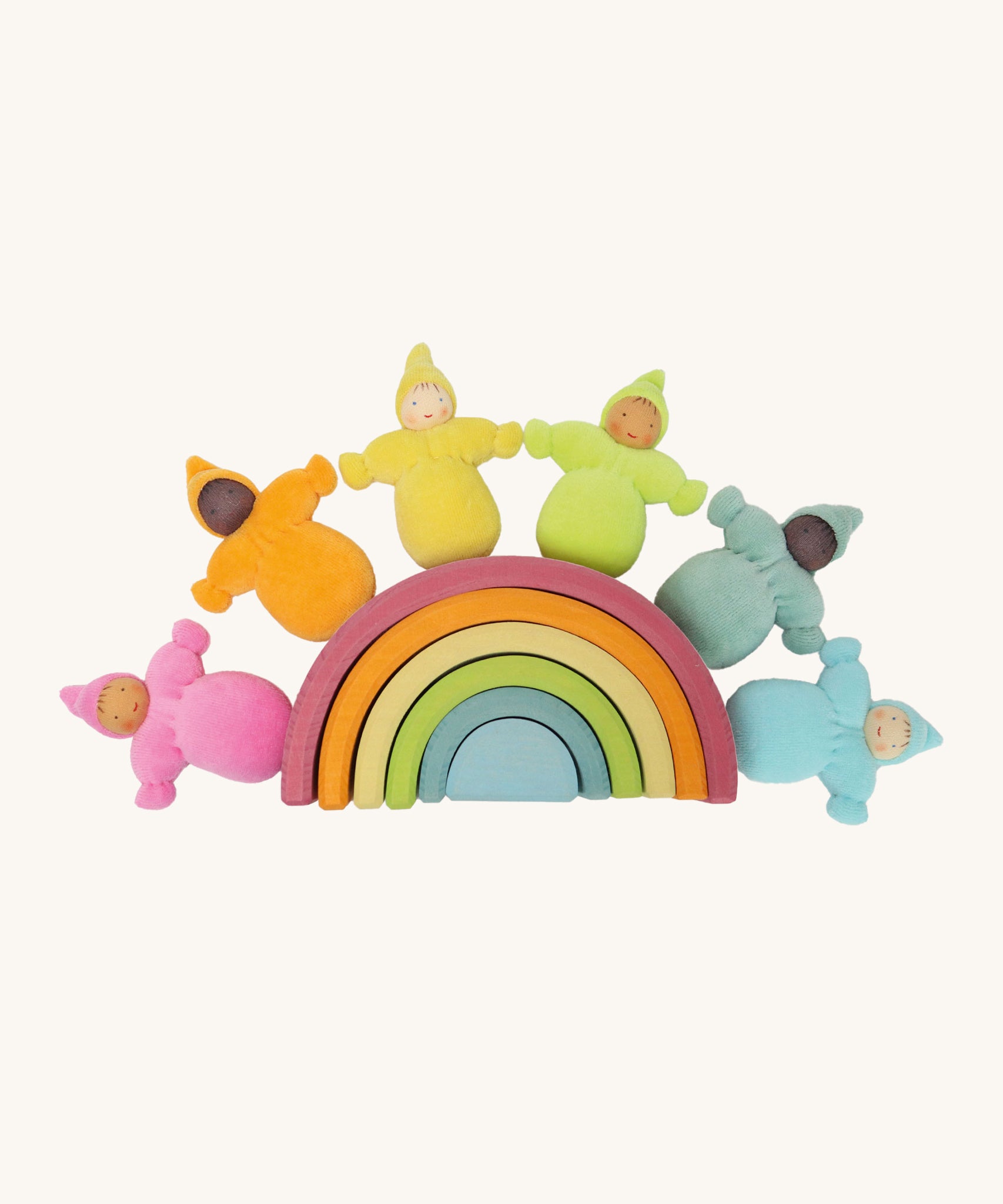 The Grimm's Pastel Dwarfs toy dolls sat on top of a grimm's small wooden pastel rainbow toy, on a cream background