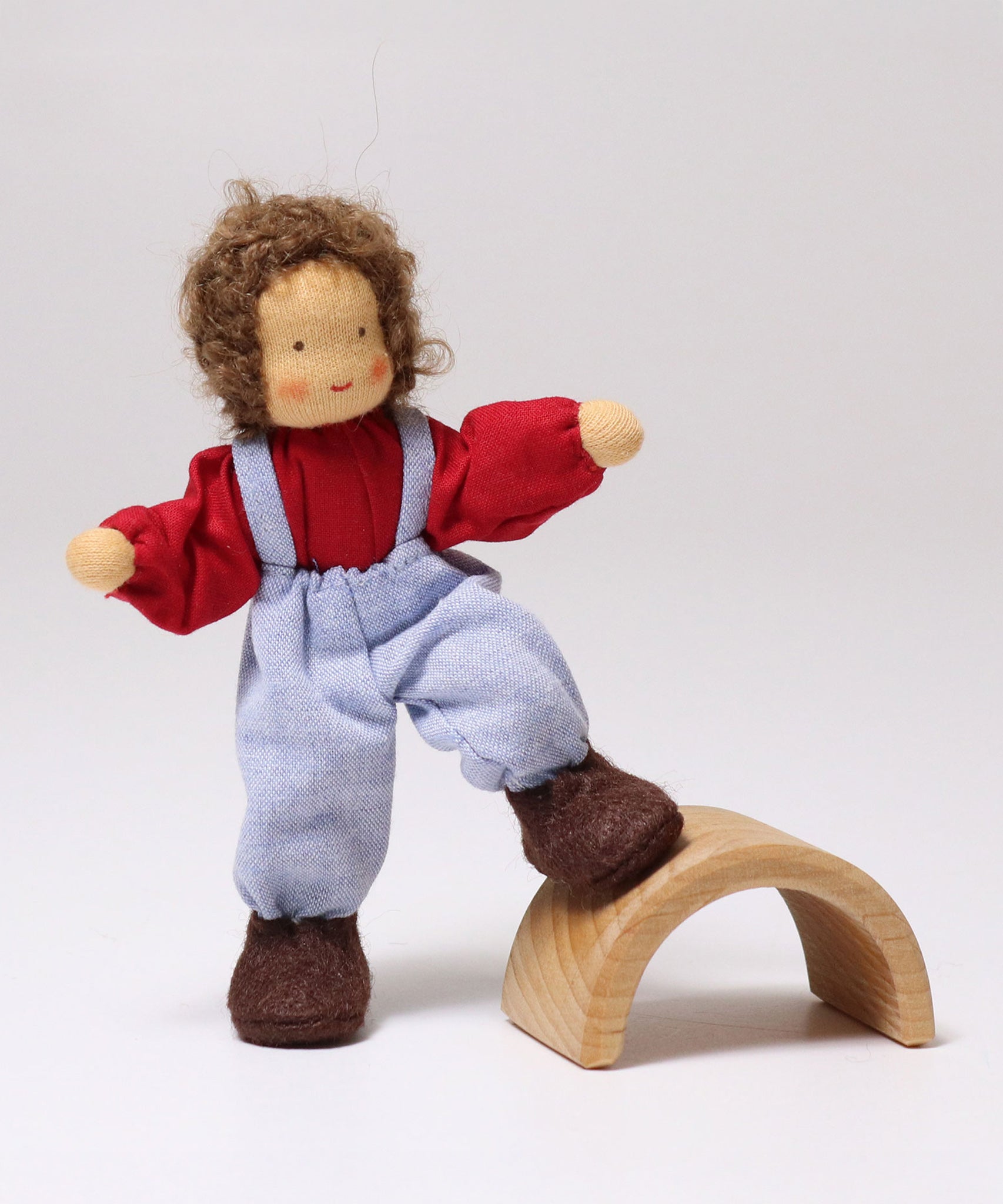 The Grimms Doll Peter has its foot on a piece of Grimm's natural rainbow, to show the flexibility of the dolls legs