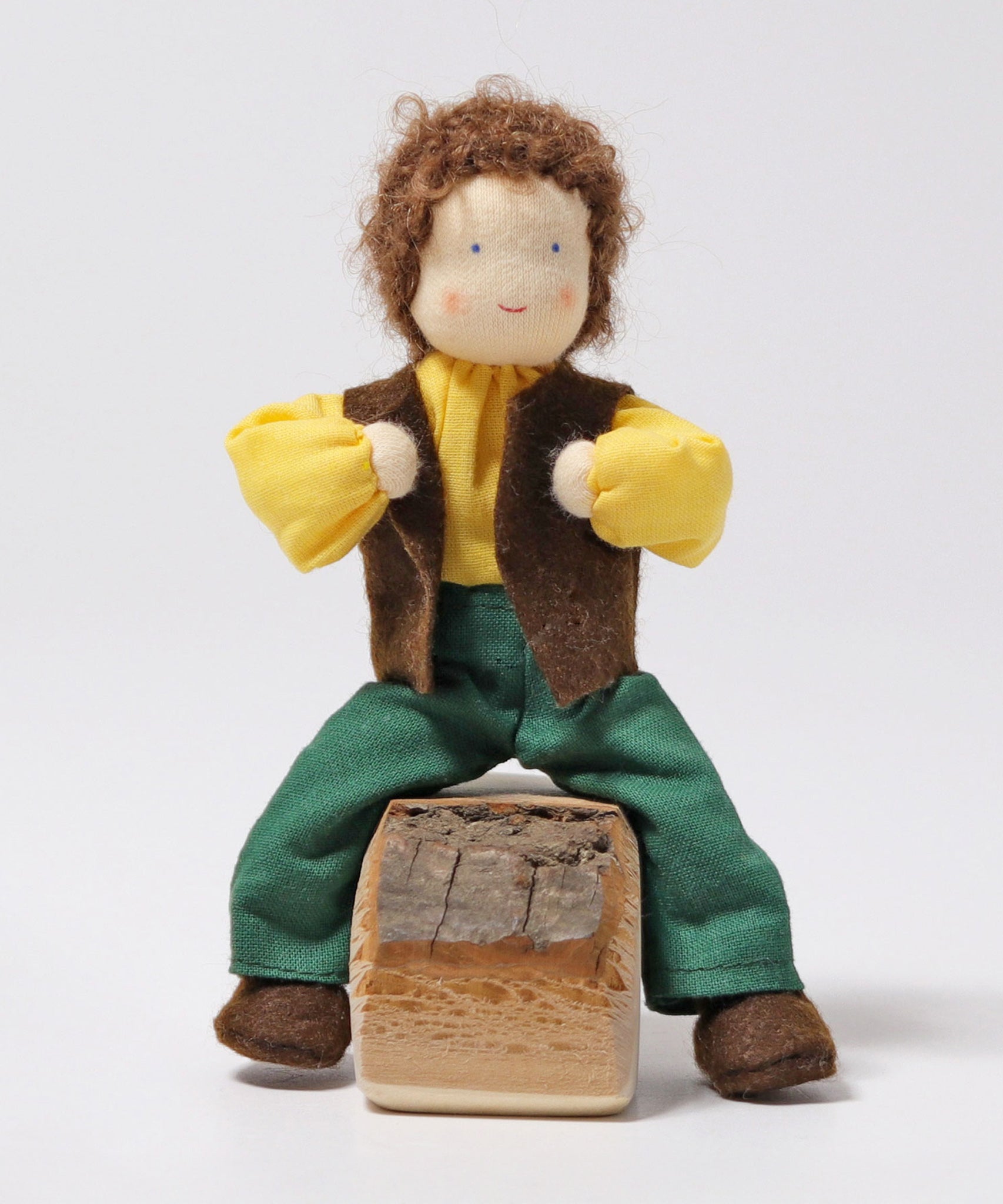 Grimm's Brown Haired Man Doll - Erle is sat down with its legs either side a wooden block of wood, and its arms bent towards its chest. This shows the flexibility of the doll