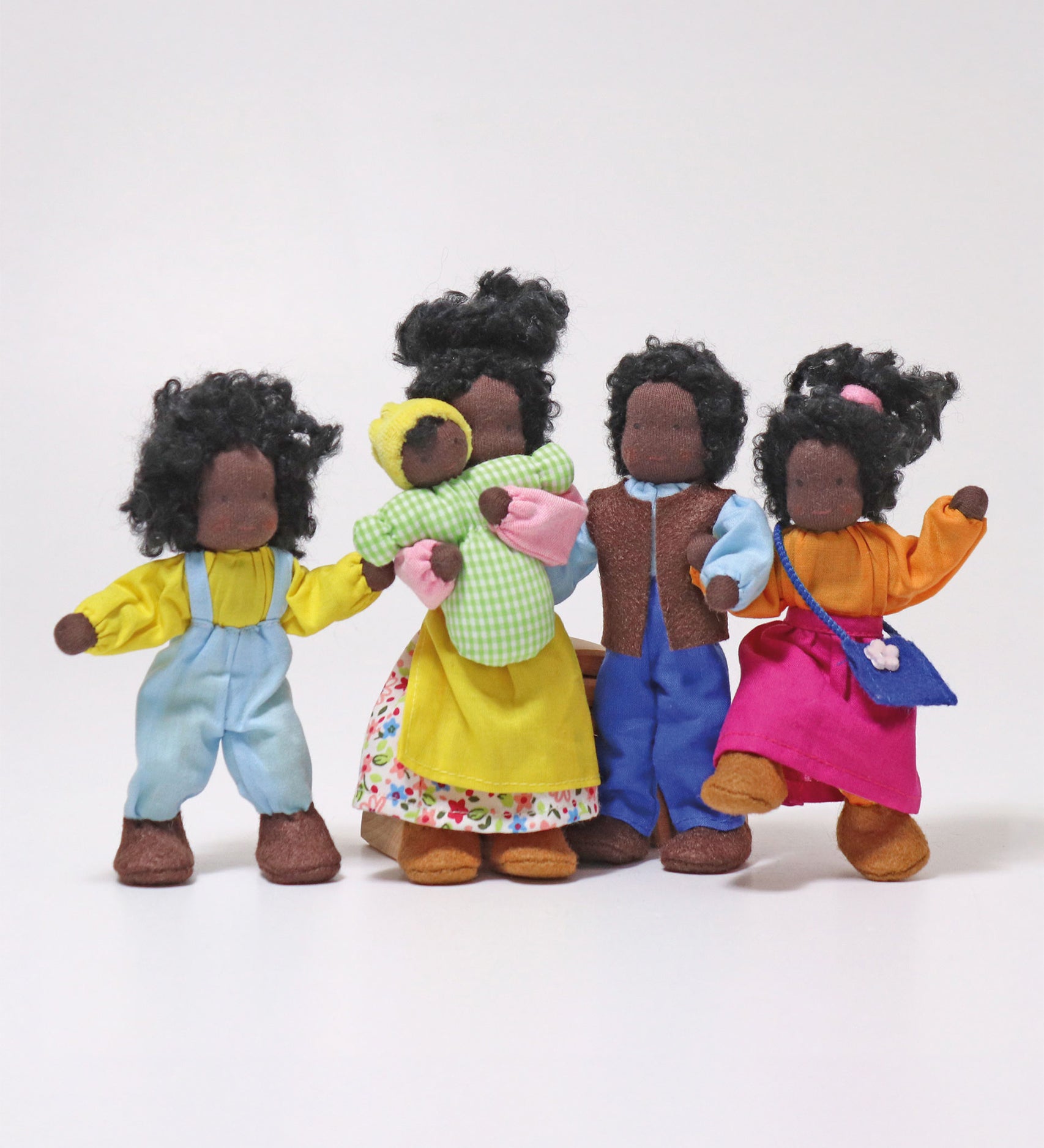 The Grimm's Handmade Waldorf Doll Family includes Mr Ebony, Mrs Ebony, Lisa, Max and Baby Sam. The dolls are all stood together with Mrs Ebony holding baby Max