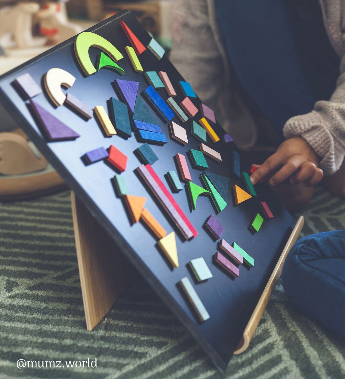 A child playing with the Grimm's Magnetic Blackboard, and has created a pattern using the Grimms magnetic puzzle pieces