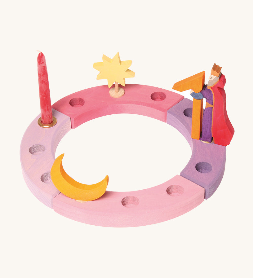 Grimm's 12-Hole Pink-Purple Wooden Celebration Ring with a candle and decorative figures on a cream background