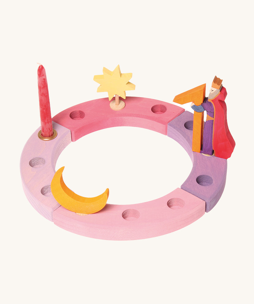 Grimm's 12-Hole Pink-Purple Wooden Celebration Ring with a candle and decorative figures on a cream background