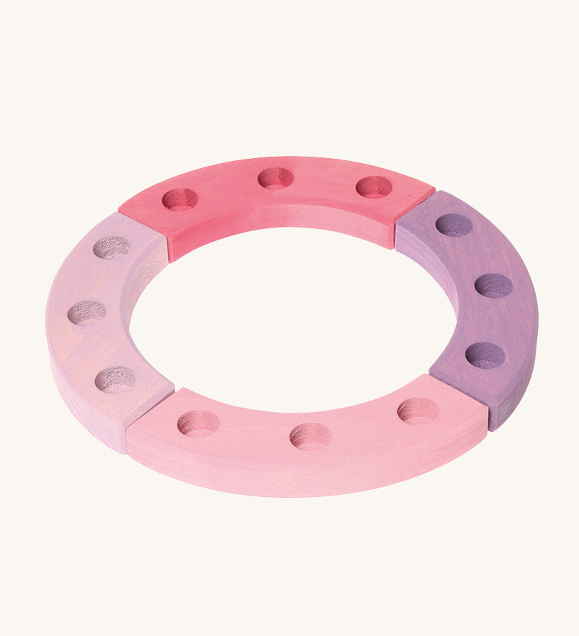 Grimm's 12-Hole Pink-Purple Wooden Celebration Ring on a cream background