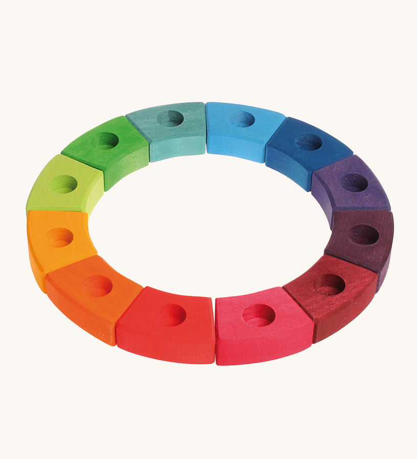 Grimm's 12-Piece Rainbow Birthday Celebration Ring on a cream background. This celebration ring has 12 individual wooden pieces each with a hole in the middle to put Grimm's decorative figures or candles inside