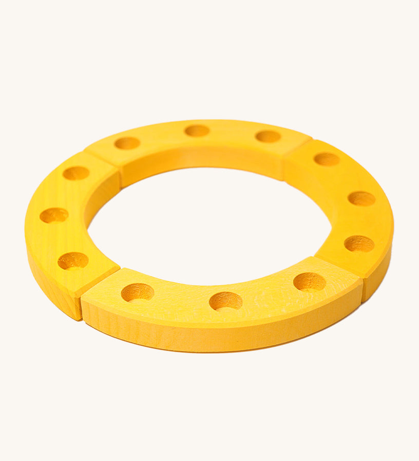 Grimm's Yellow 12-Hole Celebration Ring on a cream background. The celebration ring is made up from 4 wooden sections and has 3 small holes in each section