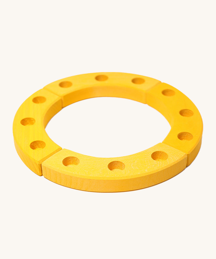 Grimm's Yellow 12-Hole Celebration Ring on a cream background. The celebration ring is made up from 4 wooden sections and has 3 small holes in each section