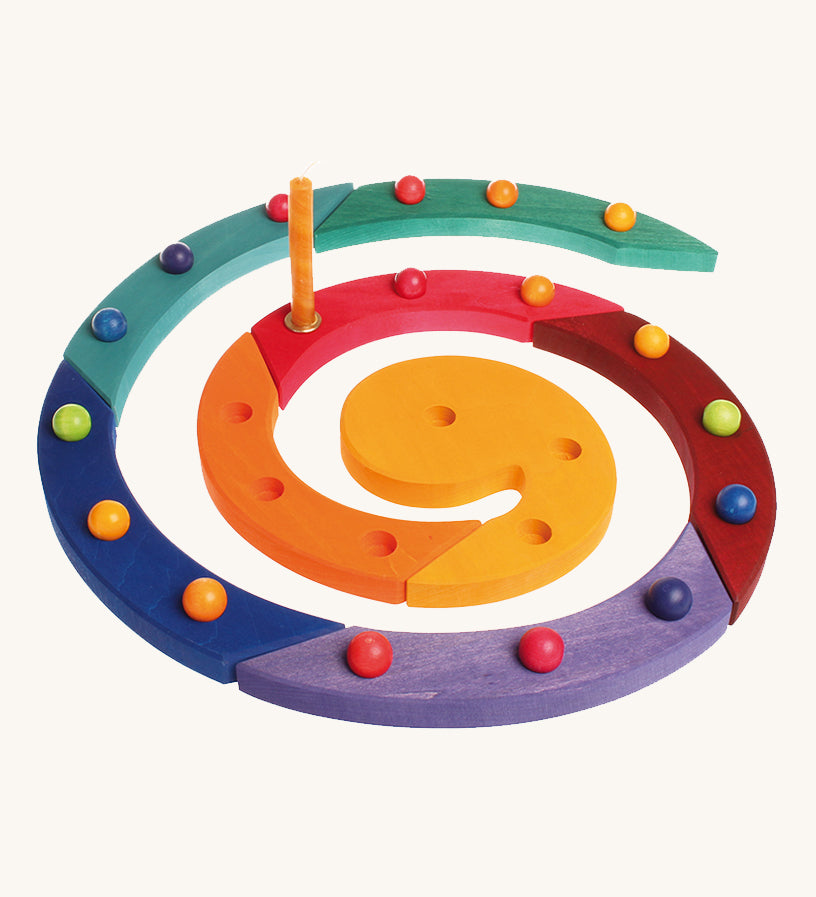 The Grimm's Coloured Wooden Spiral with marbles in each hole and an orange candle