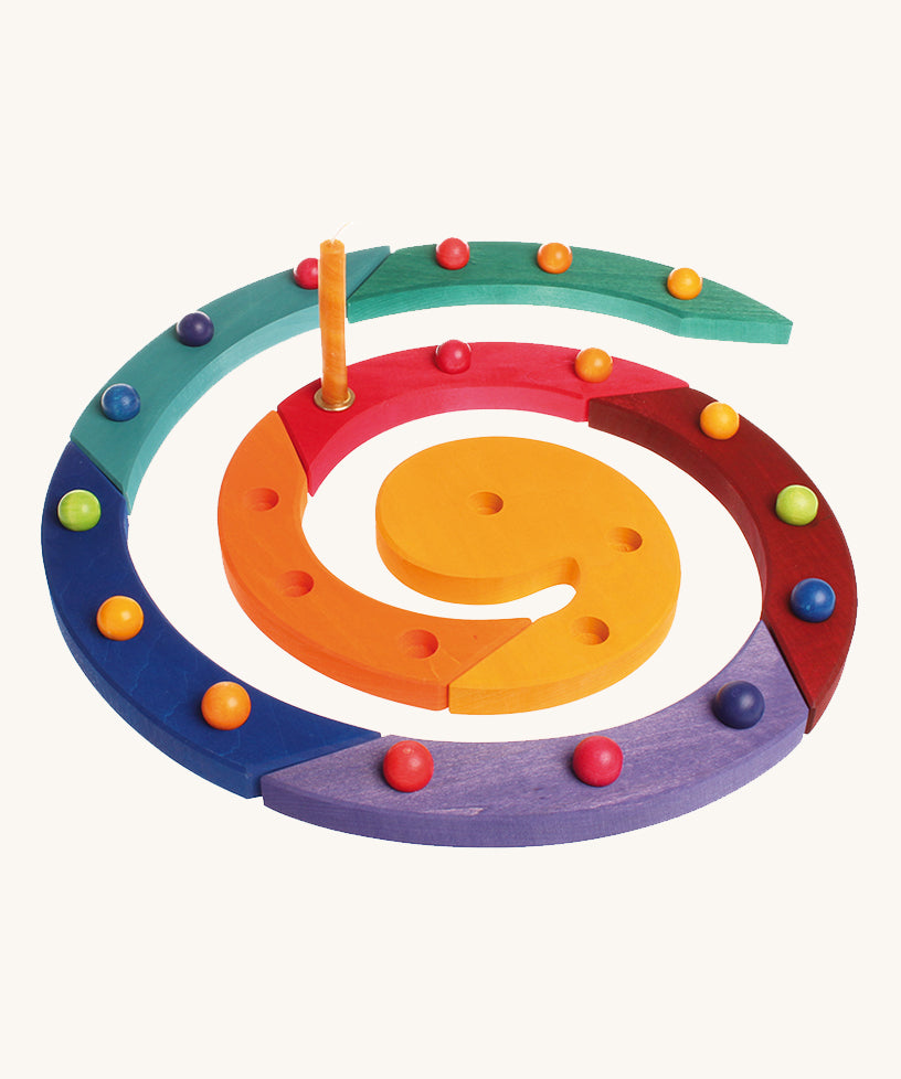 The Grimm's Coloured Wooden Spiral with marbles in each hole and an orange candle