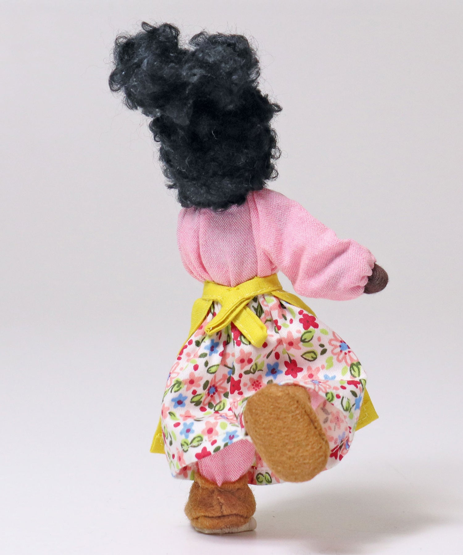 Grimm's Handmade Doll - Mrs Ebony is stood on one foot to show off the flexibility of the doll. The image shows Mrs Ebony from the back and is on a light grey background.