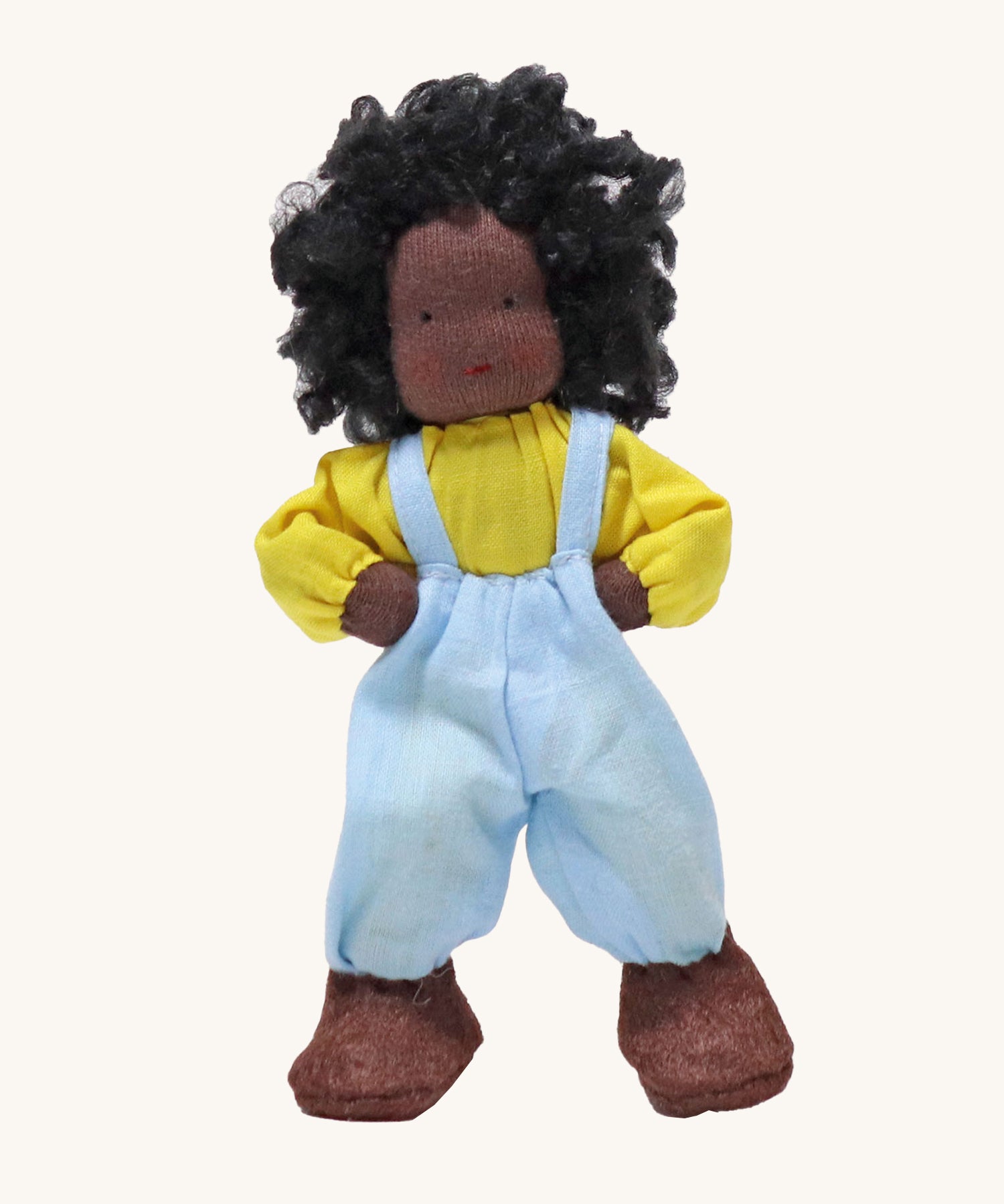 Grimm's Handmade Doll - Max is a lovely soft body doll. Max has curly black hair, black skin, a smiling face, a yellow top, light blue dungarees and brown shoes. The image is on a cream background