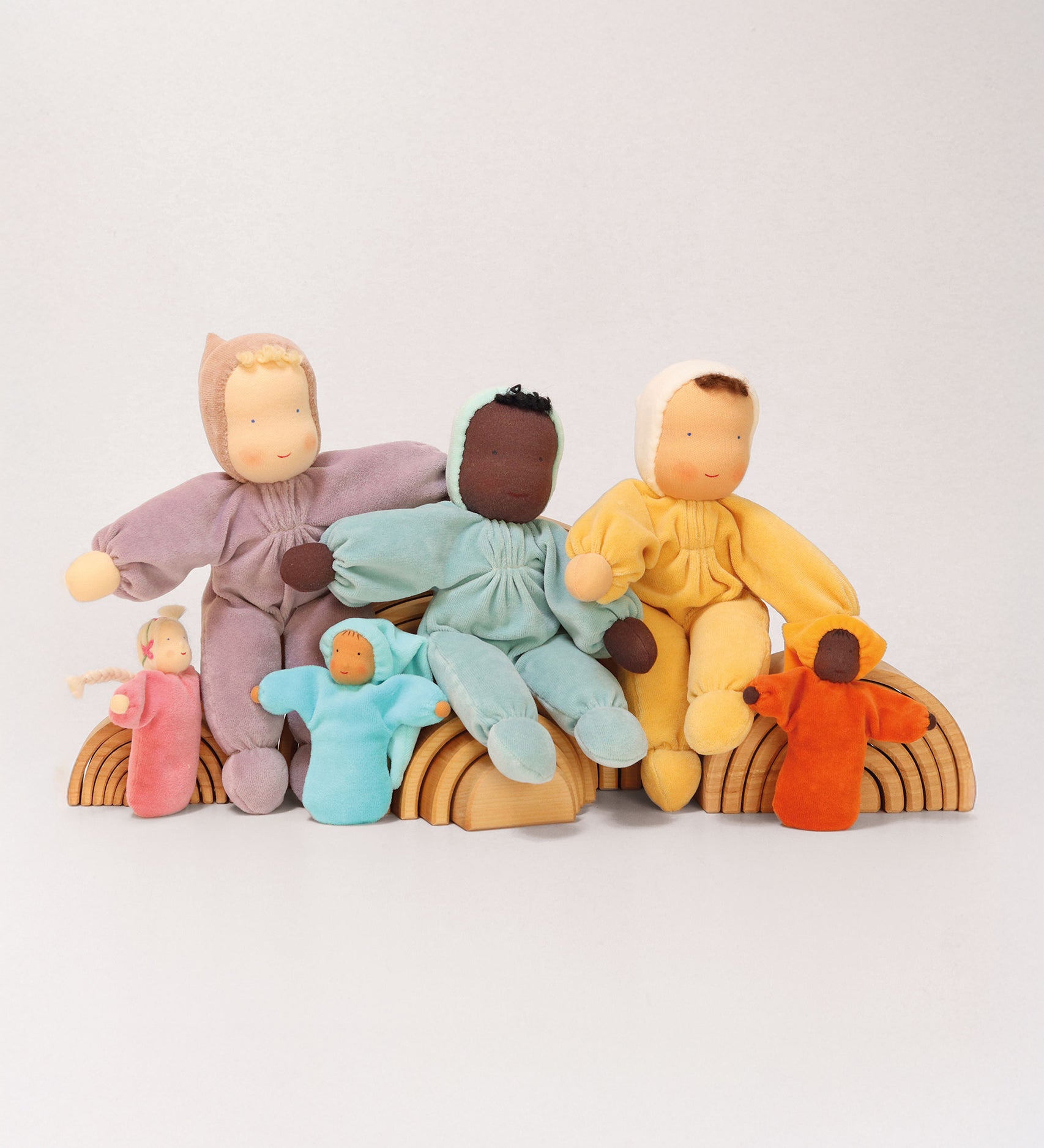 A collection of Grimm's Waldorf handmade Dolls sitting on Grimm's Natural Rainbows