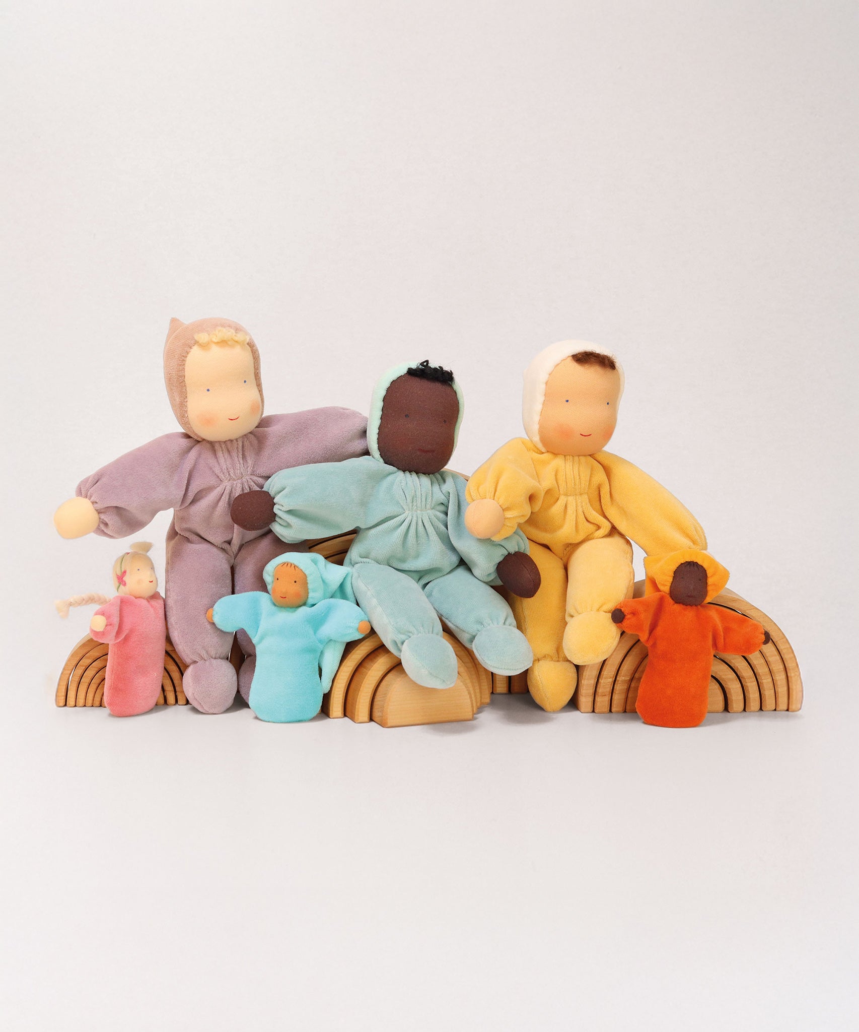 A collection of Grimm's Waldorf handmade Dolls sitting on Grimm's Natural Rainbows