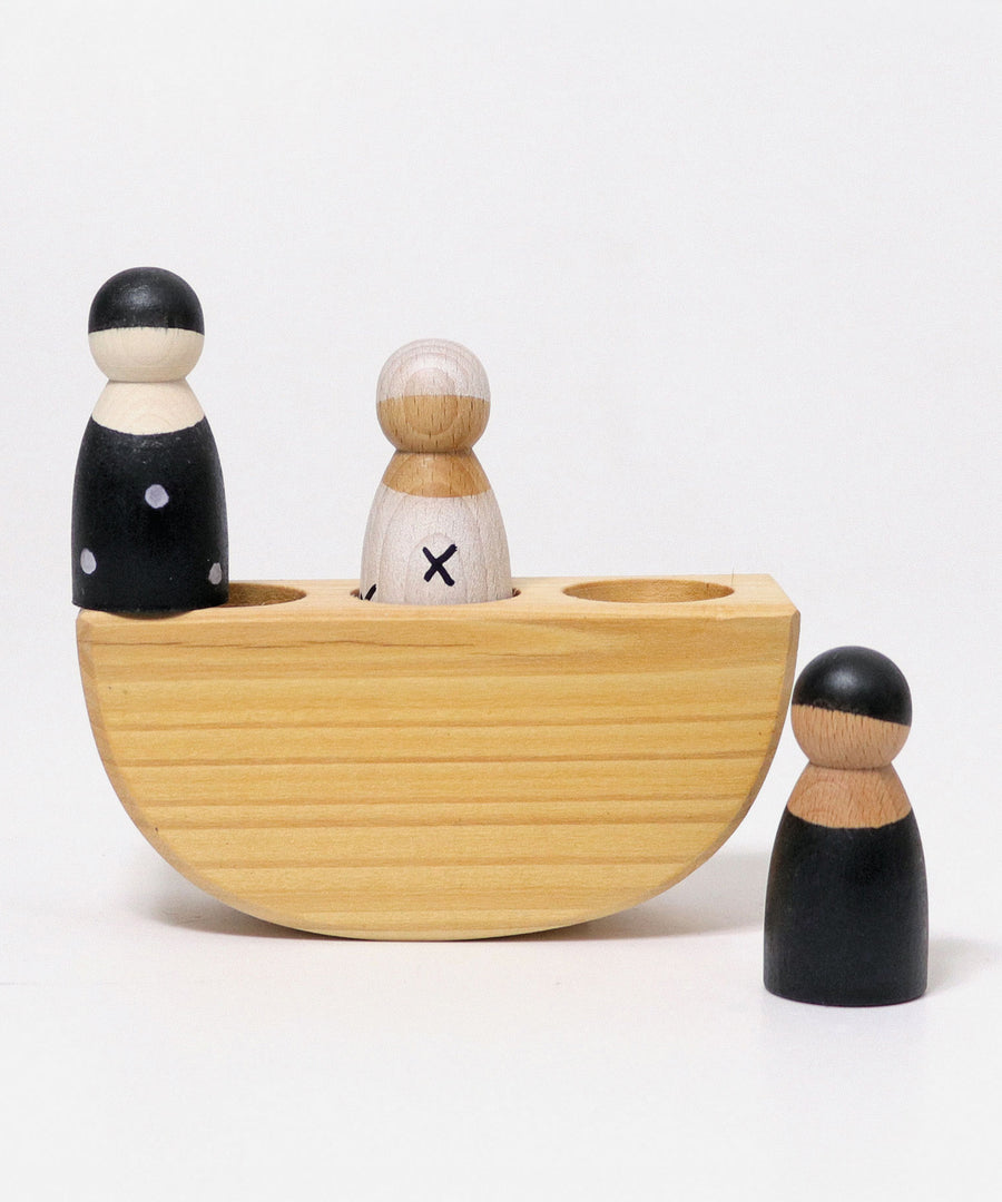 The Grimm's 3 in a Boat Monochrome showing the wooden, open ended, small world play peg dolls sat in and next to the natural wooden boat