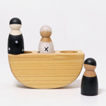 The Grimm's 3 in a Boat Monochrome showing the wooden, open ended, small world play peg dolls sat in and next to the natural wooden boat