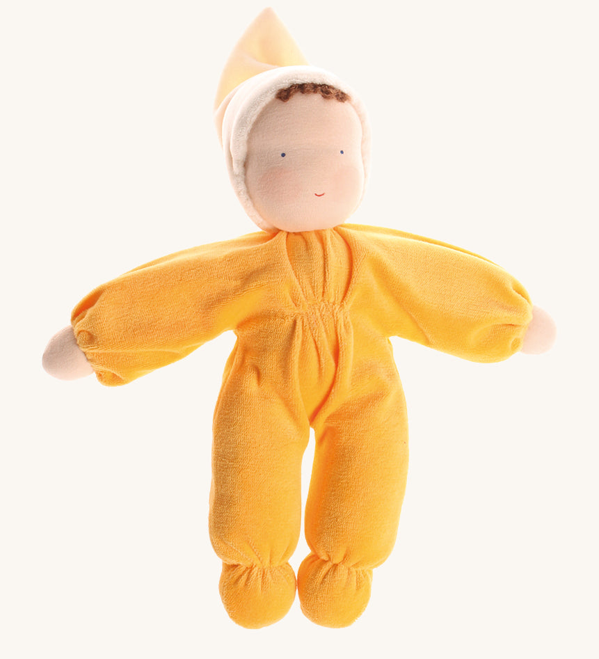 Grimm's Yellow Soft Doll is a hand-crafted Waldorf doll, wearing a yellow all-in-one baby grow with a matching night cap, with a smiling face and brown curls peeking out from under the yellow cap. The image is on a cream background