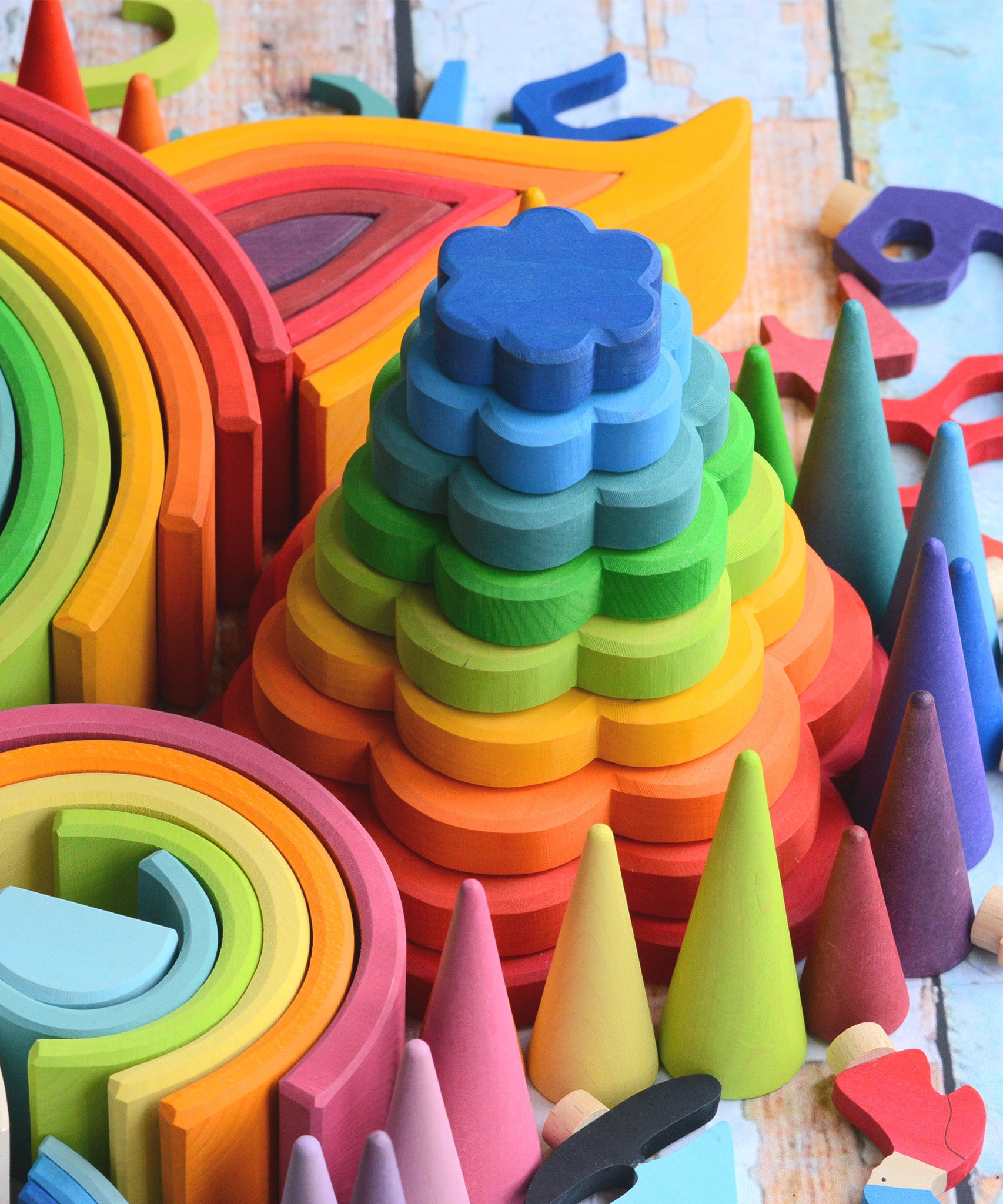 The Grimm's Stacking Flowers Tower is nestled among other Grimm's wooden toys, creating a beautiful rainbow coloured display