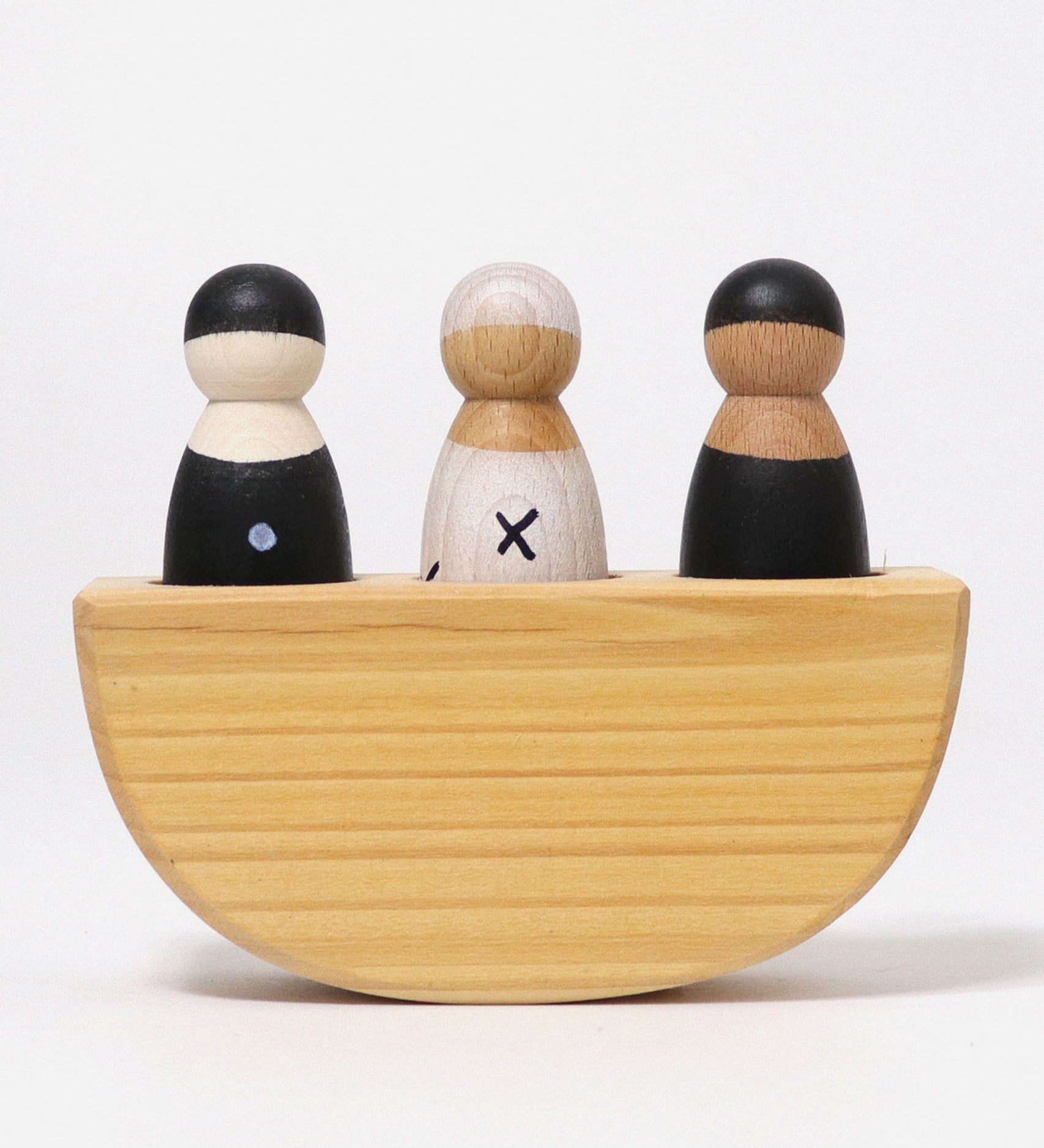 A front view of the Grimm's 3 in a Boat Monochrome kids wooden toy. The image shows the boats semi-circle shape, with the left peg dolls painted black with white spots, the middle peg doll painted white with black crosses and the left peg doll in all black