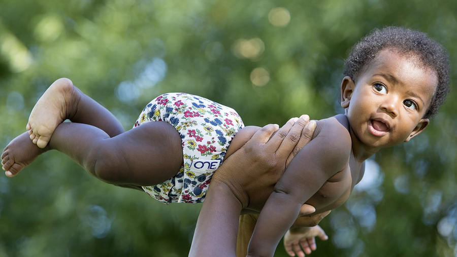 Baby wearing a GroVia nappy being held up