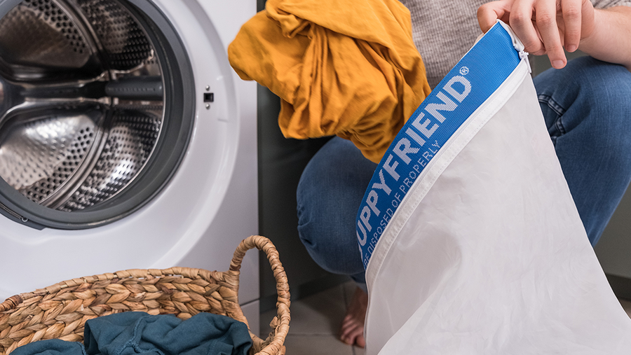 Person loading their washing machine and using a Guppyfriend washing bag