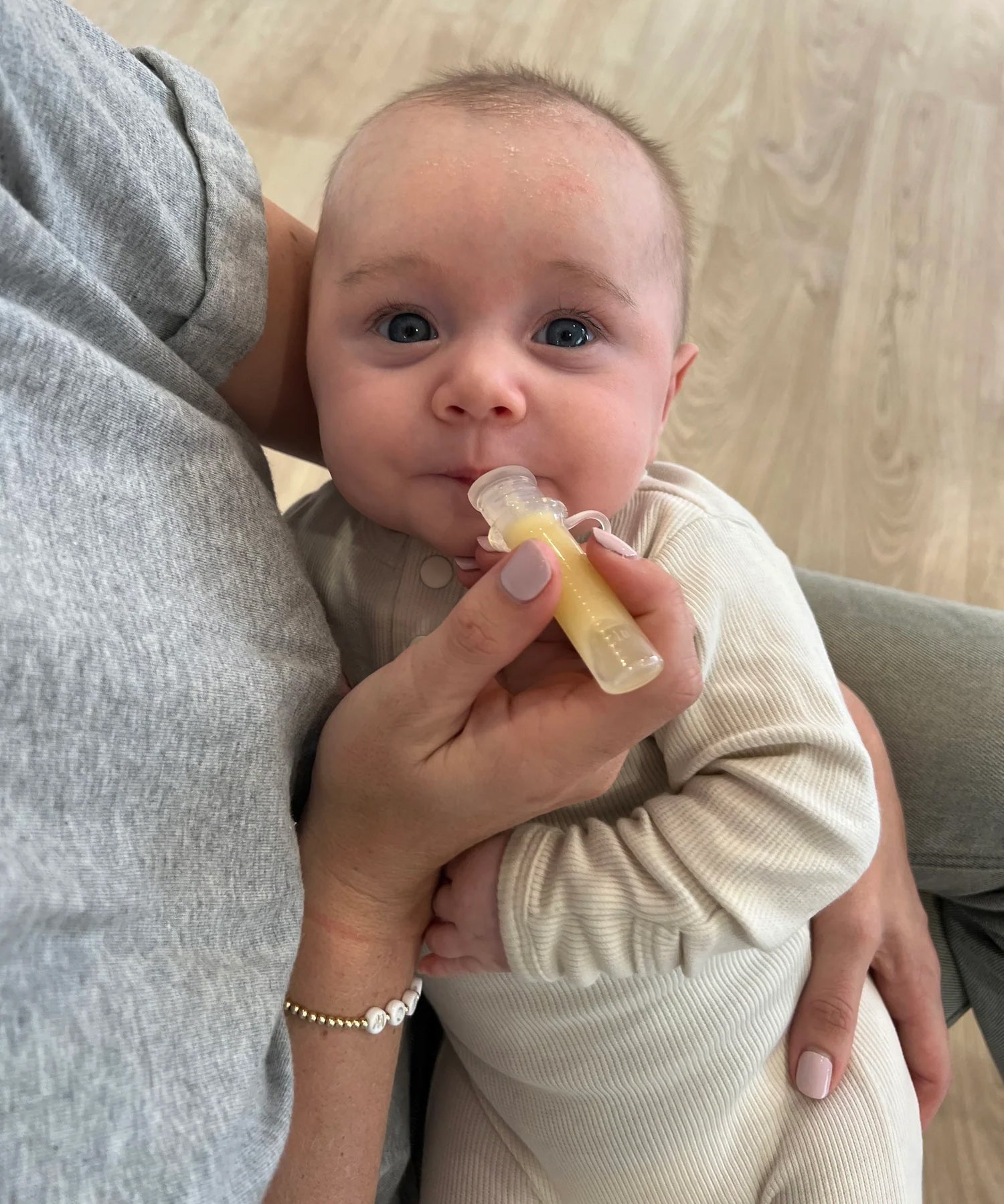 A parent is using the Haakaa Silicone Colostrum Collector with their child, laying in the parents arms