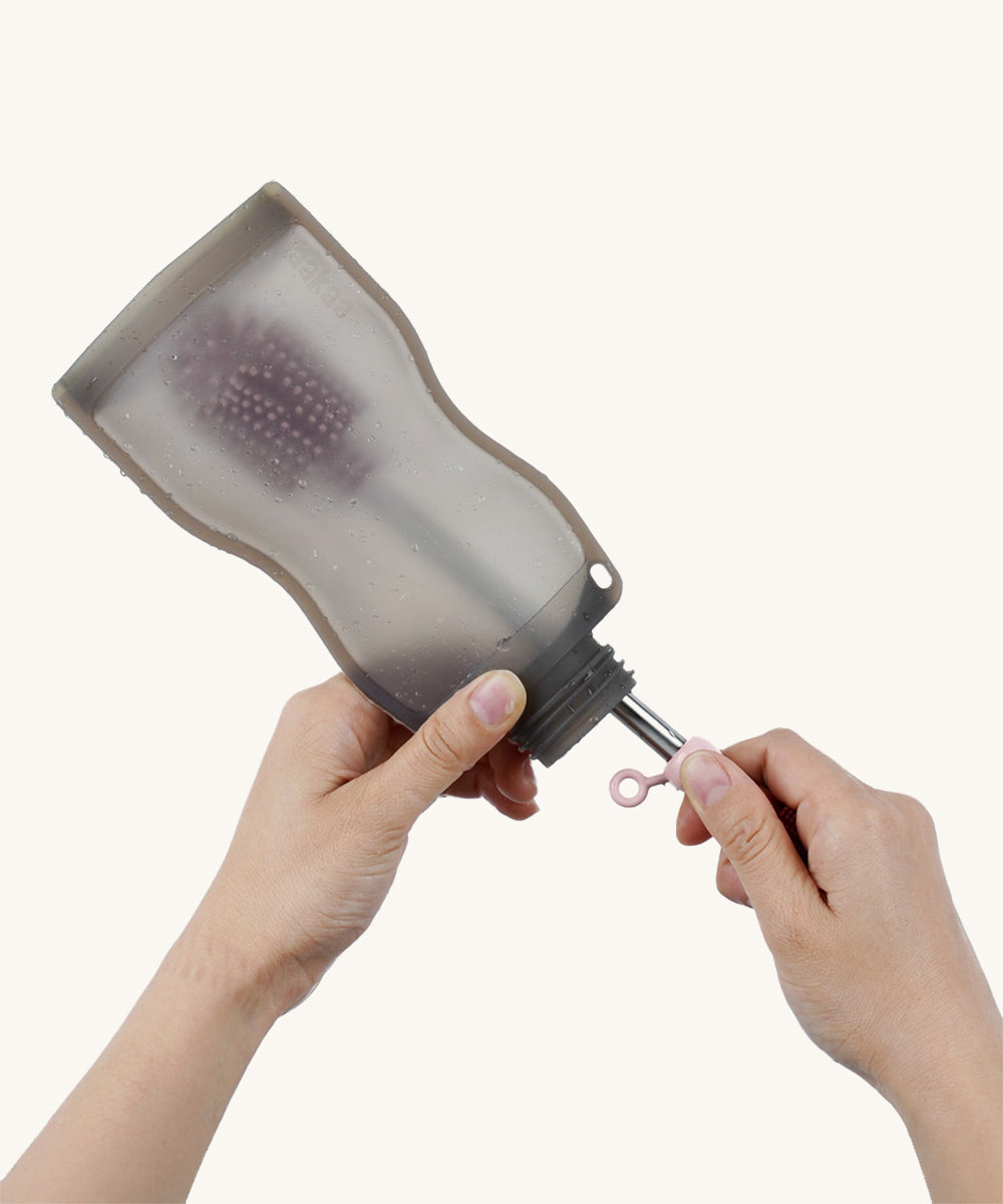 The Haakaa Silicone Cleaning Brush being used to clean a Haakaa food pouch