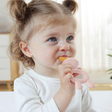 A child using the pink feeder from the Haakaa Freeze-N-Feed Mini Set. The child grasps the handle in one hand, whilst eating from the other side