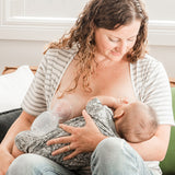 A parent breastfeeding their child, and using the Haakaa The Generation 1 100ml Silicone Breast Pump