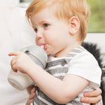 A child drinking from a Haakaa Baby Bottle, using the Generation 3 
 Silicone Bottle Handle in grey