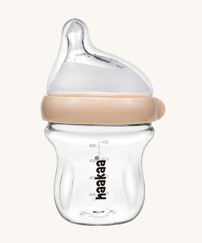 The Haakaa Generation 3 Glass Baby Bottle 120ml in peach, on a cream background