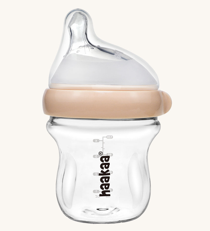 The Haakaa Generation 3 Glass Baby Bottle 120ml in peach, on a cream background