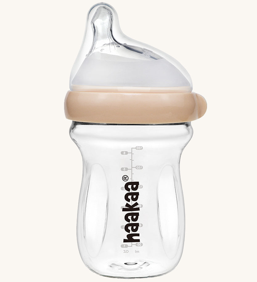 The Haakaa Generation 3 Glass Baby Bottle 180ml in peach, on a cream background