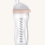 The Haakaa Generation 3 Glass Baby Bottle 300ml in peach, on a cream background