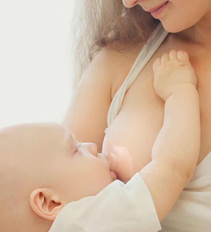 A person wearing The Haakaa Silicone Nipple Shield whilst their baby is breastfeeding 