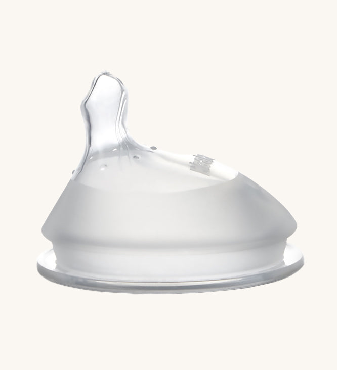 Haakaa Orthodontic Baby Bottle Nipple made from silicone with a thumb-shaped offset teat. Cream background.