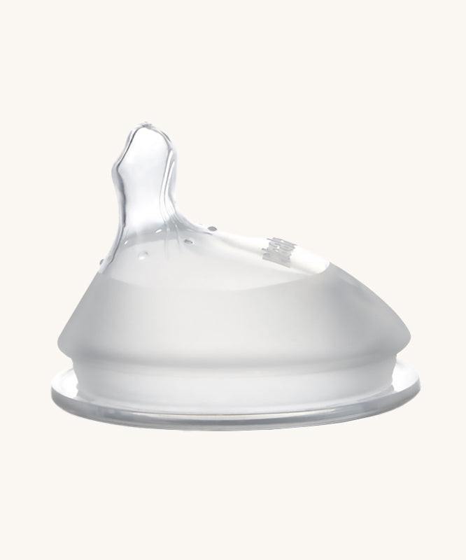 Haakaa Orthodontic Baby Bottle Nipple made from silicone with a thumb-shaped offset teat. Cream background.