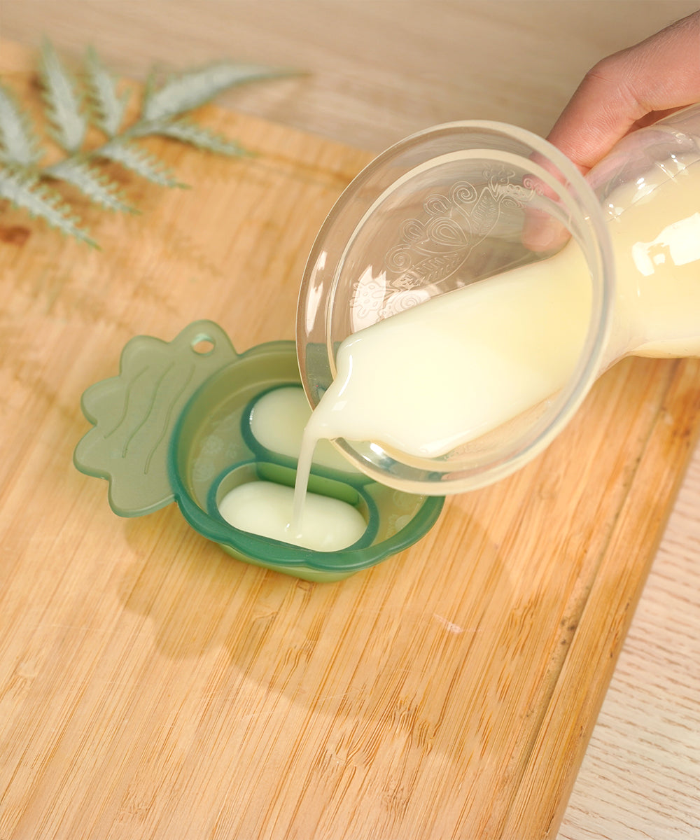 A person pouring breast milk into the Haakaa silicone Nibble Tray from the Haakaa Freeze-N-Feed Mini Set