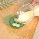 A person pouring breast milk into the Haakaa silicone Nibble Tray from the Haakaa Freeze-N-Feed Mini Set