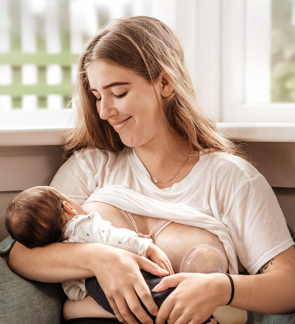 A parent breastfeeding their child, and using the Generation 1 100ml Silicone Breast Pump