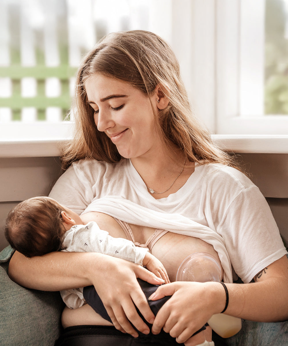 A parent breastfeeding their child, and using the Generation 1 100ml Silicone Breast Pump