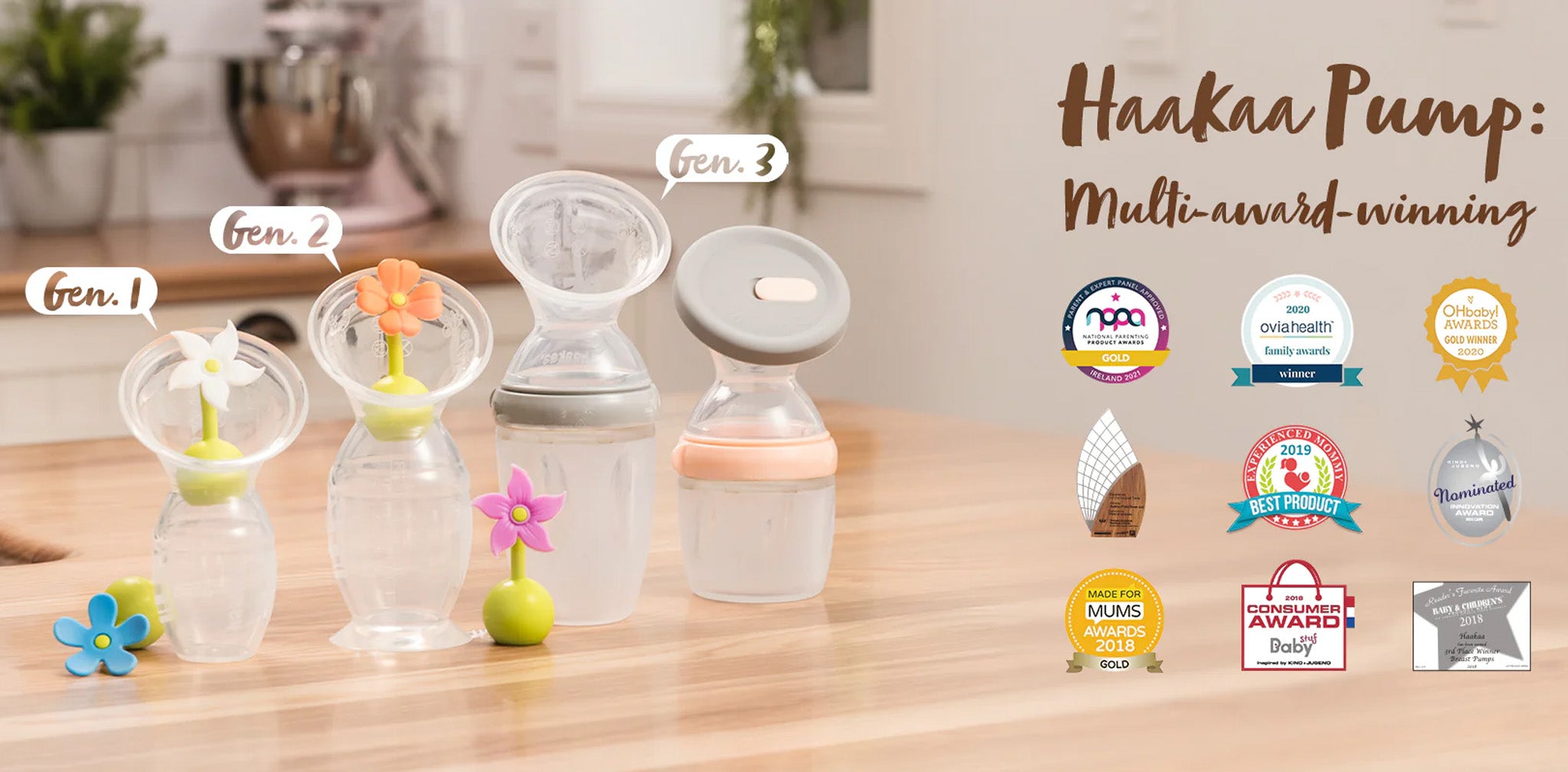 Haakaa Award-Winning Breast Pumps: A lineup of three generations of Haakaa silicone breast pumps is displayed on a wooden countertop in a bright kitchen. Each pump is labeled as "Gen. 1," "Gen. 2," and "Gen. 3," showcasing their design evolution. The first two pumps have flower stoppers in white and orange, while the third features a sleek, modern lid with a silicone seal. Surrounding the image are various award badges, highlighting the Haakaa pump as a multi-award-winning product. A blurred background incl