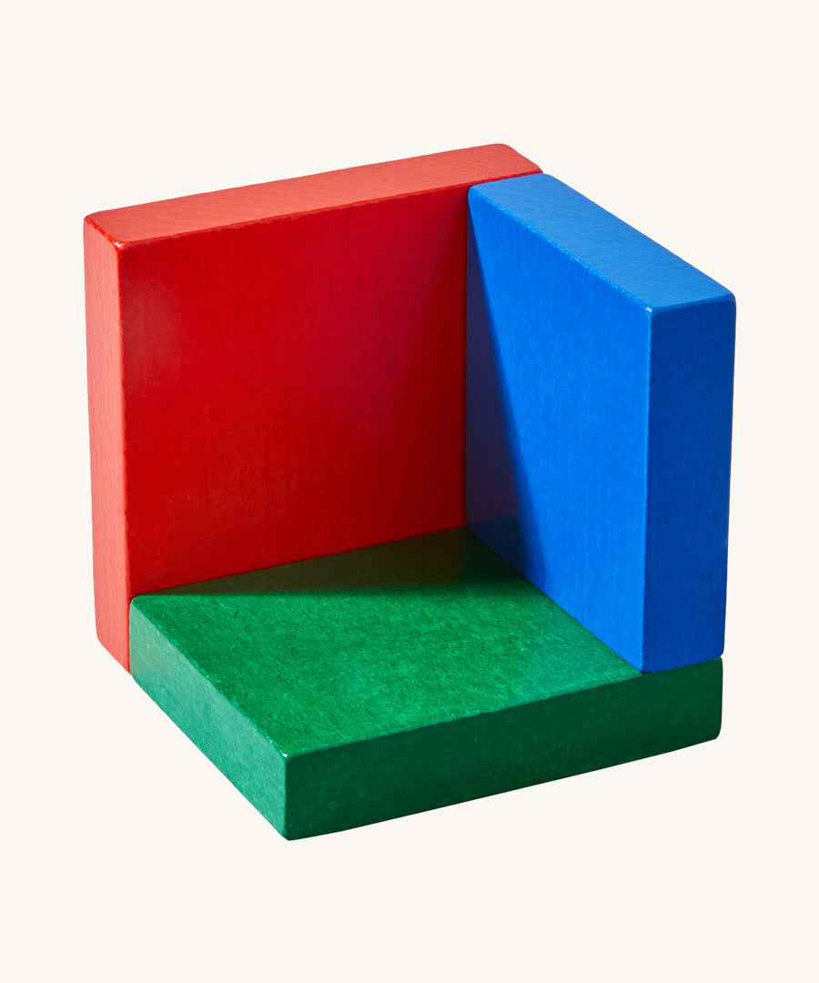 A green, blue and red piece from  the 3D Haba rainbow cube arranging puzzle on a cream background.