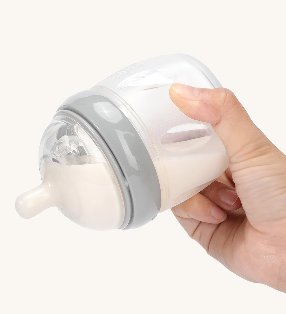 A person is tipping a Haakaa baby bottle with the Generation 3 Silicone Bottle Anti-Colic Nipple, to show that it doesn't drip when upside down