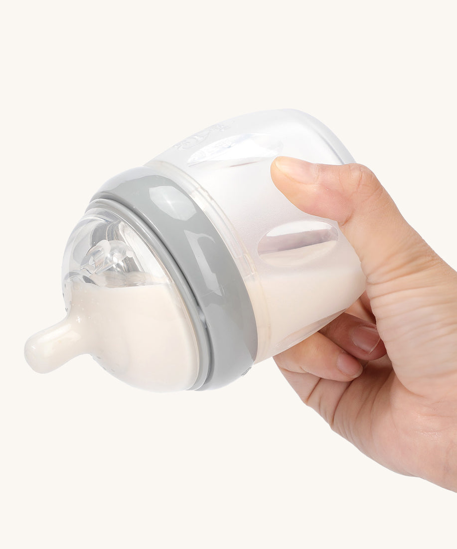 A person is tipping a Haakaa baby bottle with the Generation 3 Silicone Bottle Anti-Colic Nipple, to show that it doesn't drip when upside down