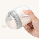 A person is tipping a Haakaa baby bottle with the Generation 3 Silicone Bottle Anti-Colic Nipple, to show that it doesn't drip when upside down